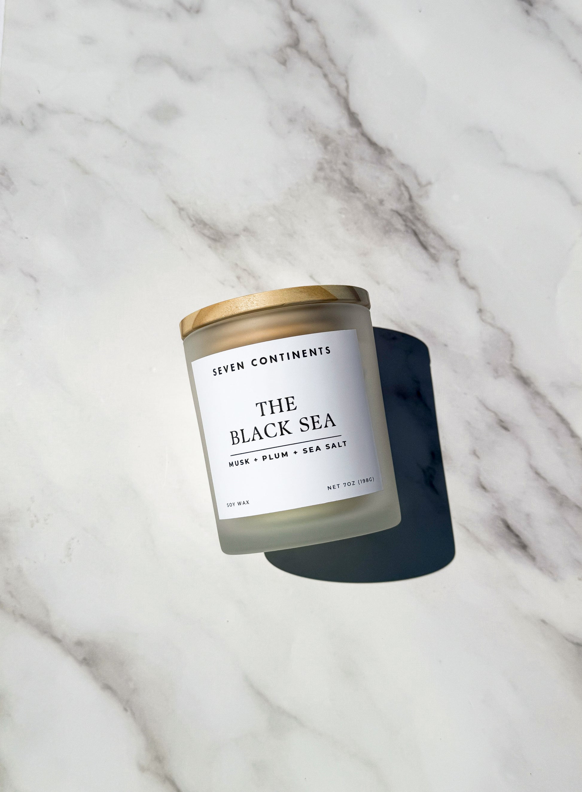 Close-up of The Black Sea candle label with plum, musk, and sea salt scent notes