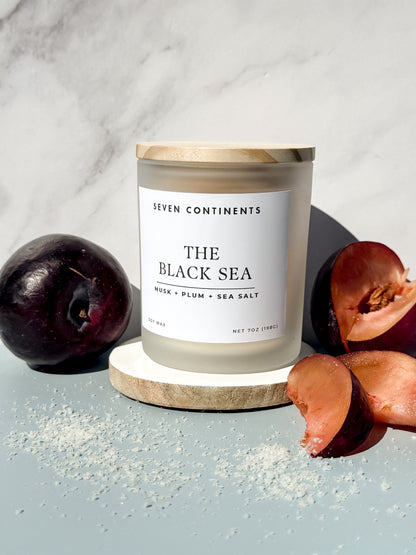 Close-up of The Black Sea candle label with plum, musk, and sea salt scent notes