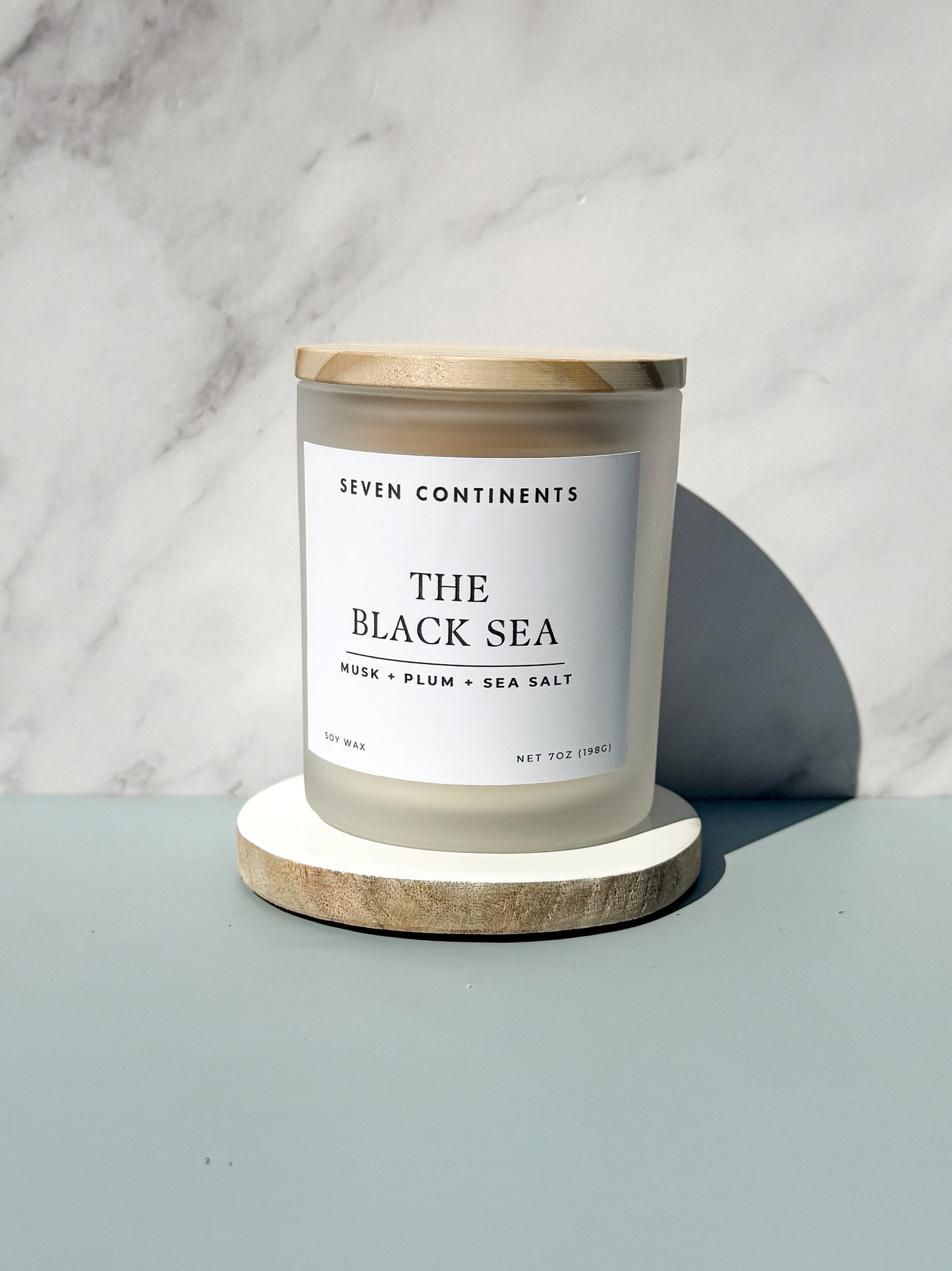 Close-up of The Black Sea candle label with plum, musk, and sea salt scent notes