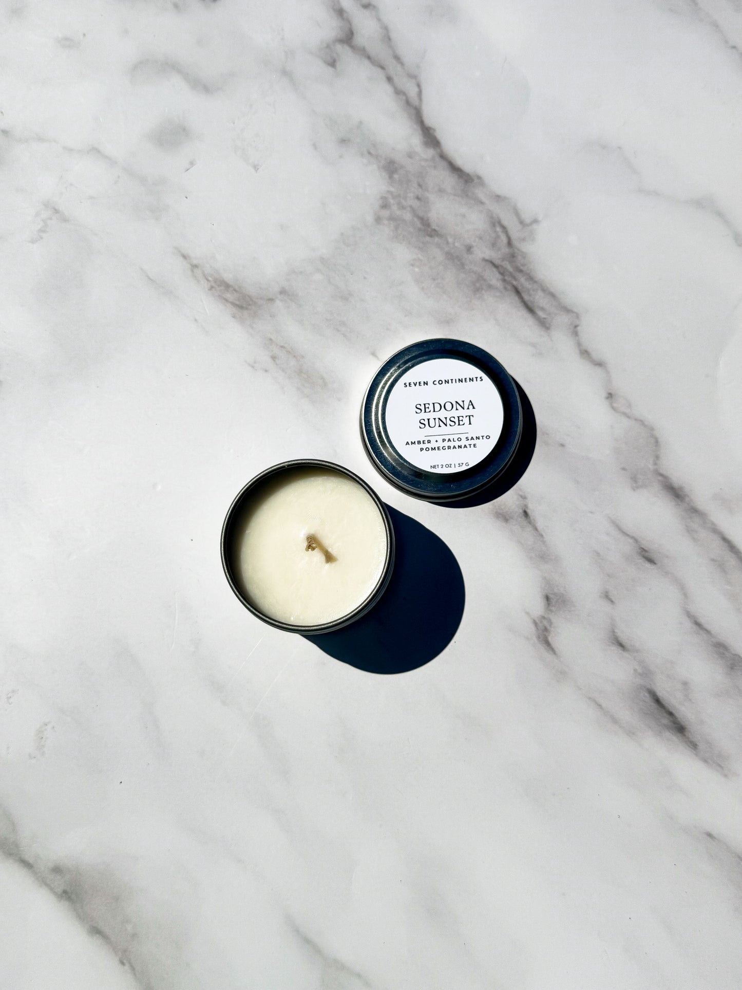Candle with lid labeled 'Sedona Sunset' on a marble surface