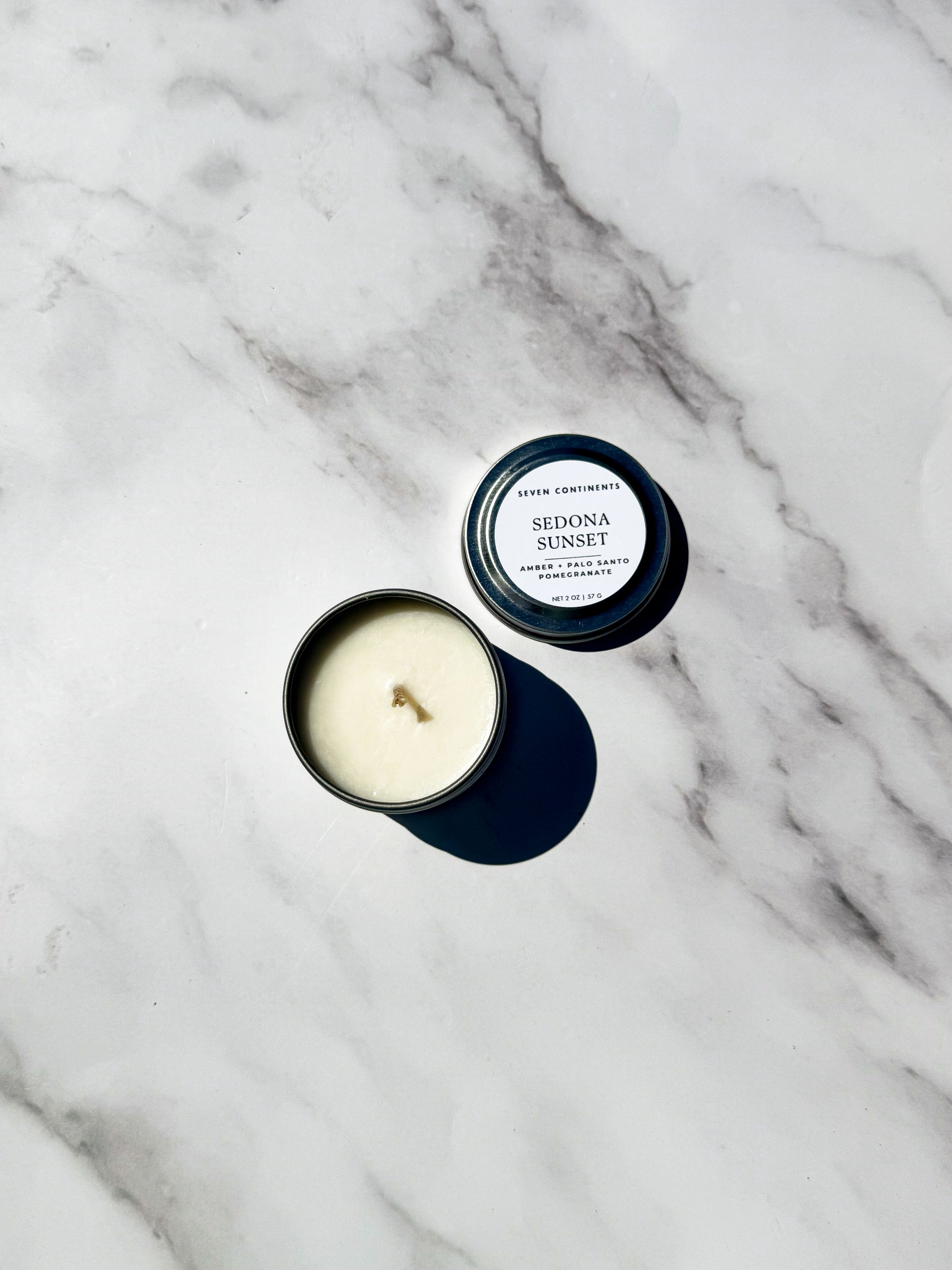 Candle with lid labeled 'Sedona Sunset' on a marble surface